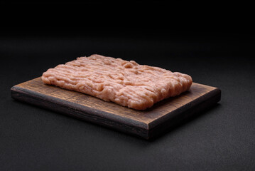 Fresh minced chicken with salt, spices and herbs on a wooden cutting board