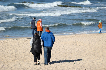 Ciepło ubrani ludzie na plaży nad morzem wiosną. 