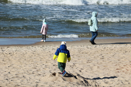 Ciepło ubrani ludzie na plaży nad morzem wiosną. 