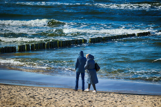 Ciepło ubrani ludzie na plaży nad morzem wiosną. 