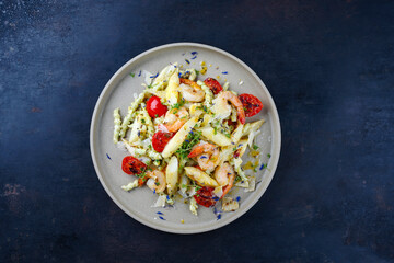 White asparagus glazed with fried king prawns and pistachio pasta served as a top view on a design plate with text space 