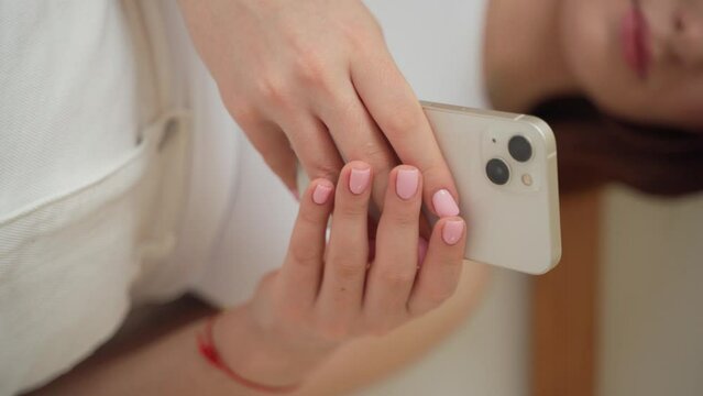 Young woman hands using smartphone close up. Vertical. Teenage girl scrolling, watching video reels, chatting, messaging social media, online shopping. Technology in daily life