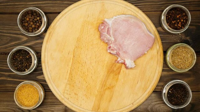 Hands lay meat on the table. Beautiful raw pink pork ribs. Cook prepares red beef steaks with spices. Spice, peppercorns, mustard, cloves, cumin, black pepper for marinating juicy meat. Cooking food
