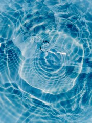 Blue water with ripples on the surface. Defocus blurred transparent blue colored clear calm water surface texture with splashes and bubbles. Water waves with shining pattern texture background.