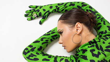 Stylish bright dancer in a bright green leopard print bodysuit, posing on the floor, studio photo on a white background. Plastic body, pretentious pose - 599707987