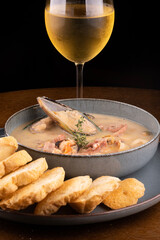 seafood soup with New Zealand mussel toast and green onion on wooden table portrait with glass of white wine close-up