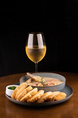 seafood soup with New Zealand mussels toast and green onions on wooden table portrait with glass of white wine