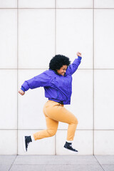 afro woman jumping on white wall, copy space for social media