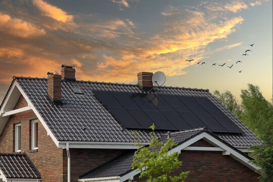 Brick house, solar panels, beautiful sunset. Roof and photovoltaic.