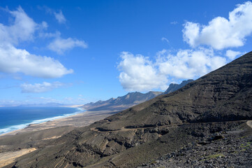 View on difficult to access golden sandy Cofete beach hidden behind mountain range on Fuerteventura, Canary islands, Spain