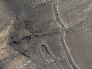 Dangerous dirty road to golden sandy Cofete beach hidden behind mountain range on Fuerteventura, Canary islands, Spain, aerial view