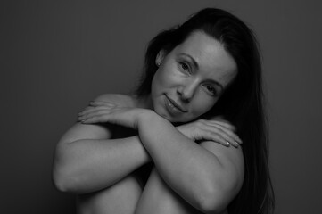 Black and white portrait of a naked woman without makeup. Natural female portrait with first wrinkles and plump lips