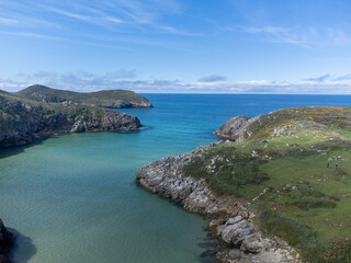 Aerial view on Playa de Poo during low tide near Llanes, Green coast of Asturias, North Spain with sandy beaches, cliffs, hidden caves, green fields and mountains.