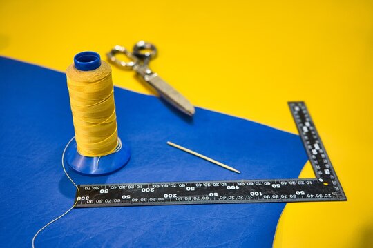 Forbici, righello e filo da cucito su sfondo giallo e blu, colori dell'ucraina, lavoro del tappezziere e del cucito