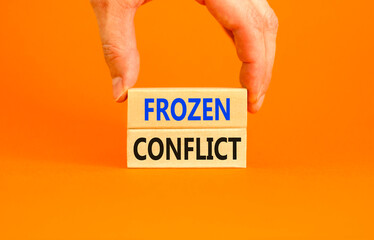 Frozen conflict symbol. Concept words Frozen conflict on beautiful wooden block. Beautiful orange table orange background. Businessman hand. Business and Frozen conflict concept. Copy space.