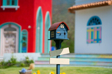 Mailbox on the lawn in front of colorful houses in the background during morning light, letterbox, house shape mailbox. have a mail in your mailbox house