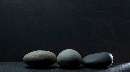gray zen stones on a dark gray background with shadows for a podium background.a group of oval...