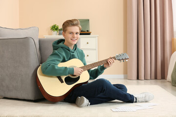 Teenage boy playing acoustic guitar in room
