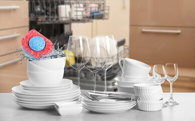 Many clean tableware in kitchen. Dishwasher detergent falling into bowl with water