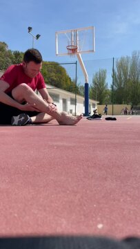 Adult caucasian barefoot basketball player wearing red t-shirt screaming with painful facial expression due to accident. Inflamed Articulation. Swollen Joint. Vertical 4K 60fps video footage