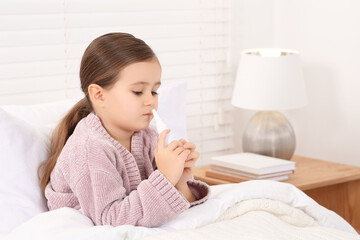 Little girl using nasal spray in bedroom