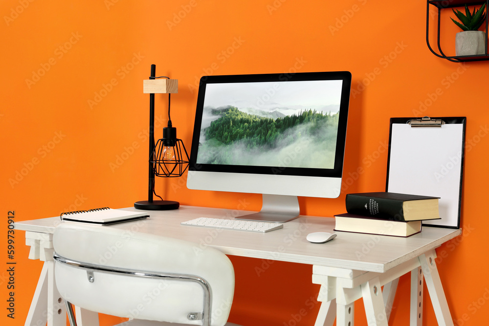 Canvas Prints Modern computer, books, lamp and notebook on wooden desk near orange wall. Home office