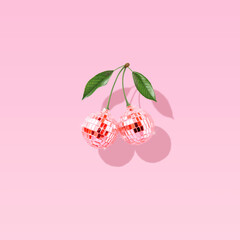Modern retro composition made of decorative disco balls like cherries on a pastel pink background....