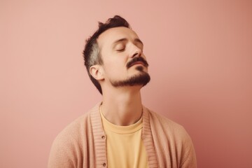 Obraz premium Portrait of a handsome young man with closed eyes on a pink background