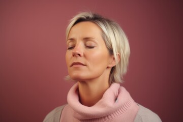 Fototapeta premium Portrait of a woman with closed eyes on a pink background.