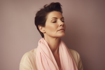 Fototapeta premium Portrait of a beautiful young woman in a pink scarf on a pink background