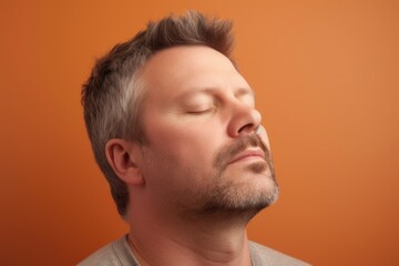 Fototapeta premium Portrait of a man with closed eyes on a orange background.