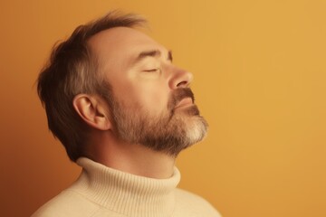 Obraz premium Portrait of a bearded man in a white sweater on a yellow background