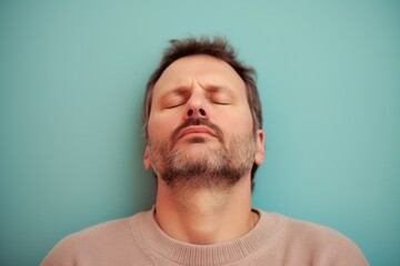 Obraz premium Close up portrait of a man sleeping on a blue background in the studio