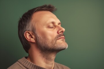 Portrait of a handsome man with closed eyes on a green background