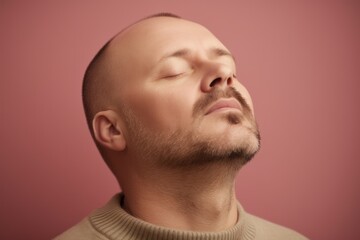 Fototapeta premium Portrait of a man with closed eyes on a pink background.