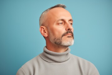 Fototapeta premium Portrait of a mature man in a gray sweater on a blue background