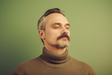 Portrait of a man in a sweater on a green background.