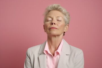 Portrait of mature woman with closed eyes, isolated on pink background