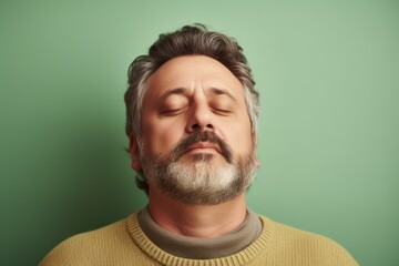 Fototapeta premium Portrait of a middle-aged man with gray hair and beard on a green background