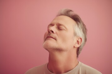 Fototapeta premium Portrait of a handsome man with gray hair on a pink background