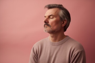 Portrait of a middle-aged man in a pink sweater on a pink background