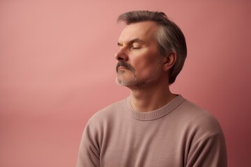 Fototapeta premium Portrait of a middle-aged man in a pink sweater on a pink background