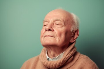 Obraz premium Portrait of an elderly man with closed eyes on a green background