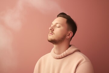 Young man with closed eyes and dreamy expression on pink background.