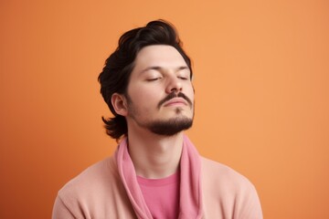 Obraz premium Portrait of a handsome young man with closed eyes on orange background