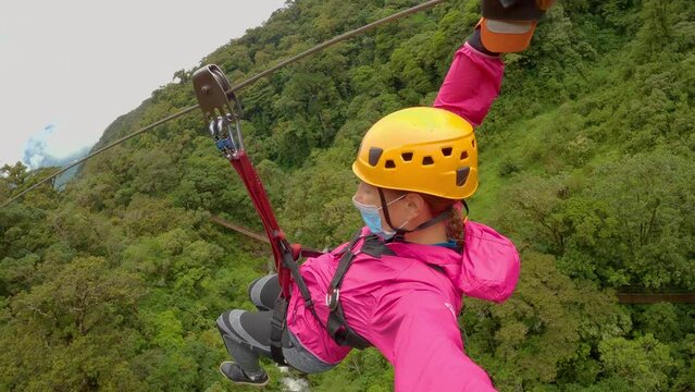 Joyful zipline ride above lush jungle trees of an adventurous lady in Panama. She is having an adrenaline experience in pristine rainforest while holidays in mountain town Boquete in Chiriqui Province
