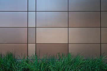 Tan and Brown Block Wall with Green Plants in the Foreground.