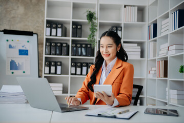  Beautiful Asian business woman typing laptop and tablet Placed at the table at home office