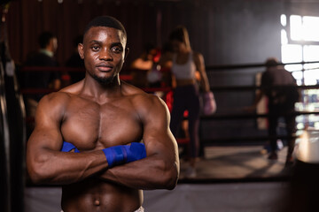 Fototapeta na wymiar Young confident African American boxer standing in pose and ready to fight, stadium background.