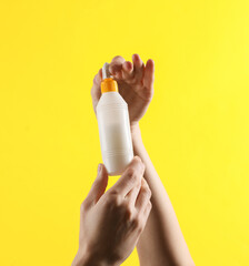 Female hands holding glue bottle on yellow background